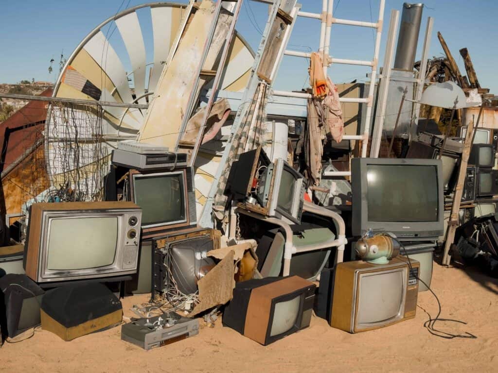 Pile of old televisions and scrap metal in a junkyard