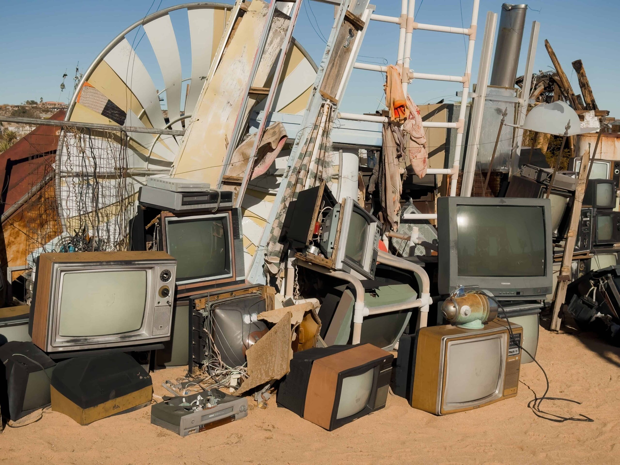 Pile of old televisions and scrap metal in a junkyard